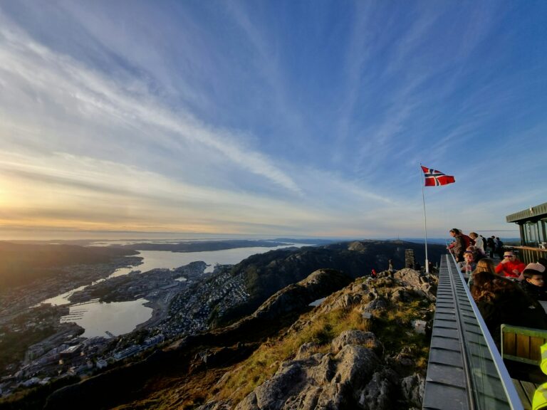 View of Bergen from the city mountain on a clear summer day, with the Norwegian flag in the wind under blue skies