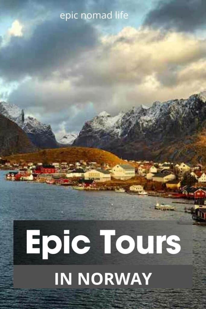 Best tours in Norway, photo from northern norway with the dark polar waters in front of a quaint village, and in the background are wild dark mountains where the peaks are covered in snow!