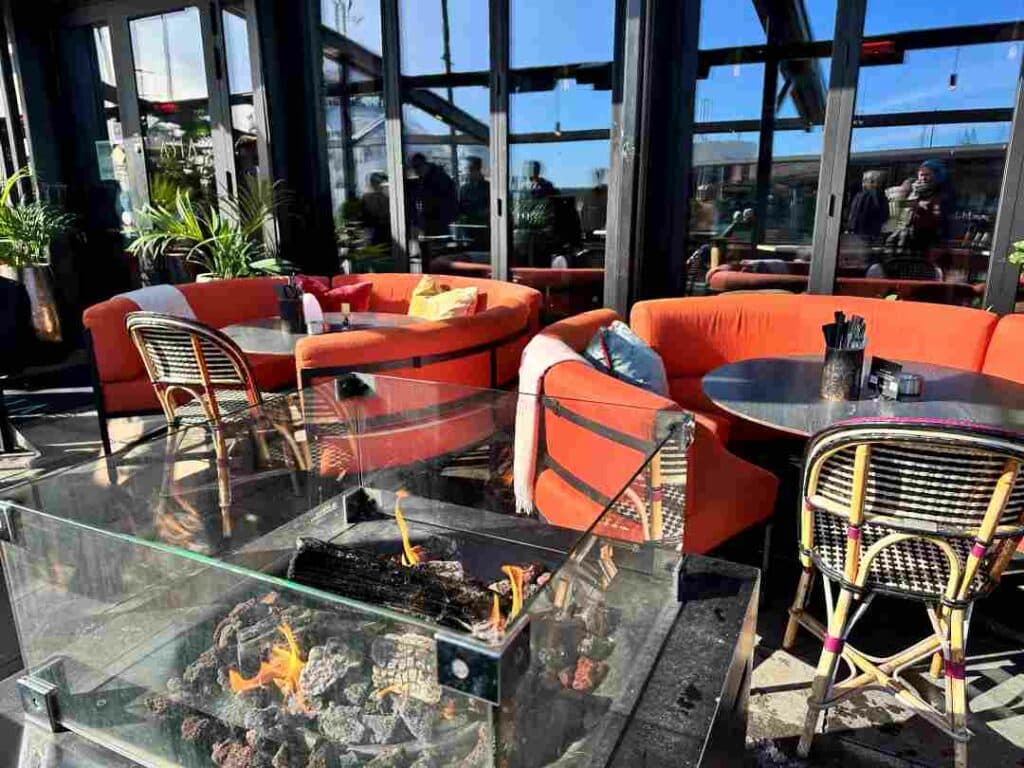 Outdoor seating in red sofas next to a  fireplace in Aker Brygge on a sunny day
