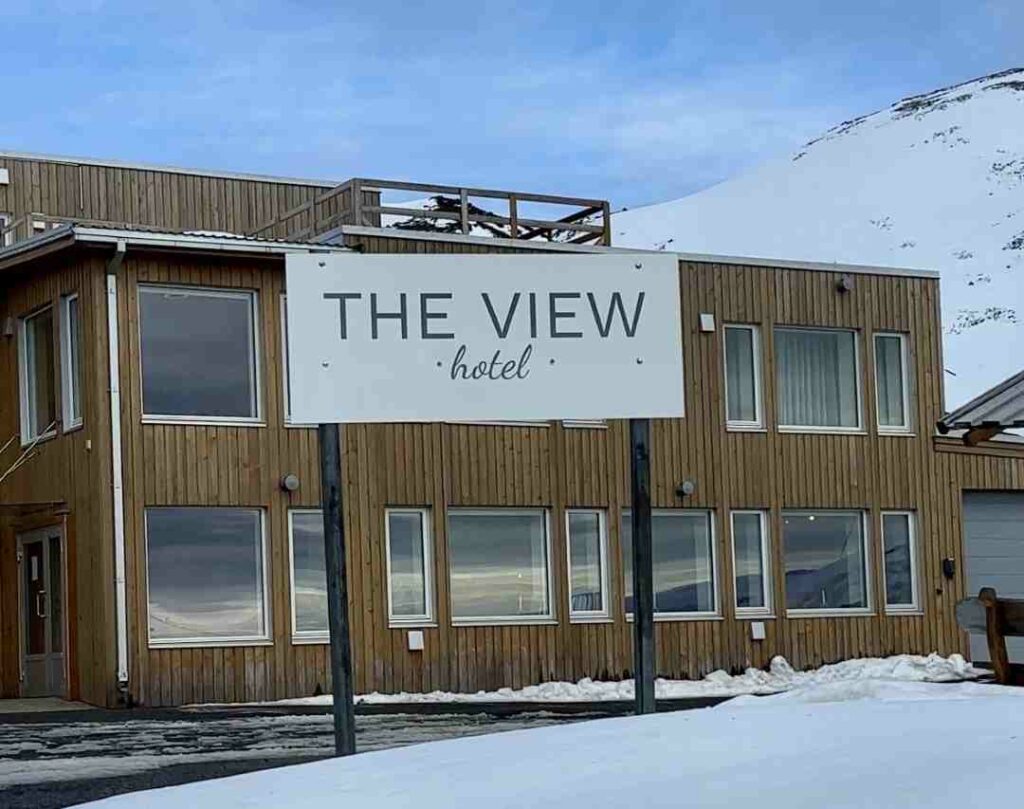 The light wooden modern The View Hotel in Honningsvåg, nestled under the barren rugged Arctic mountains on a spring evening in blue lights