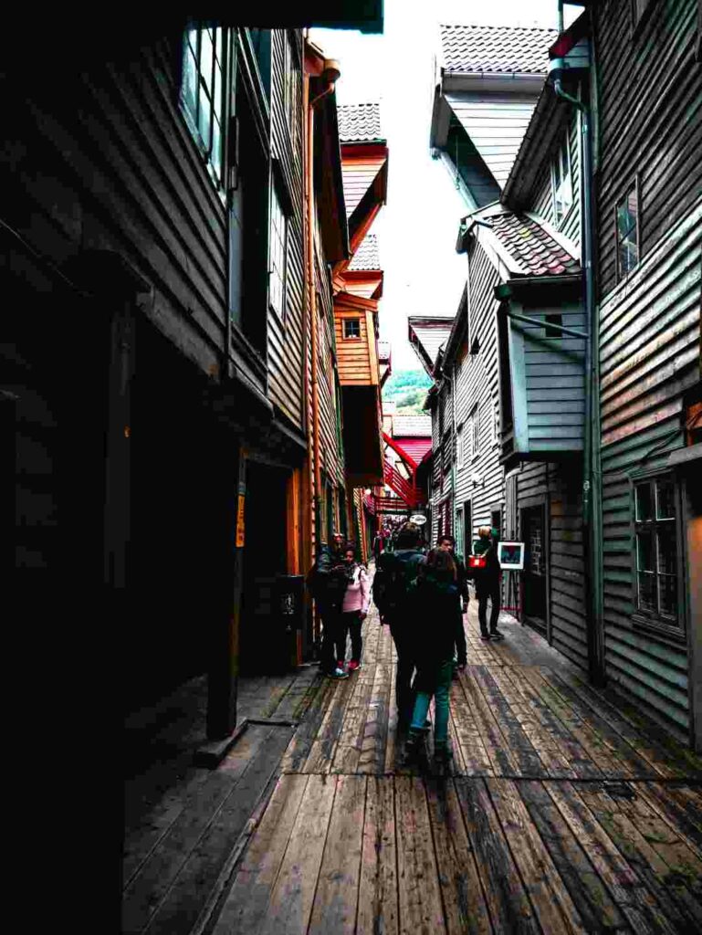 Skostredet alley in Bergen, where the floor and houses are all made from wood, with intricate details in the architecture "cramped" inot a narrow charming alley