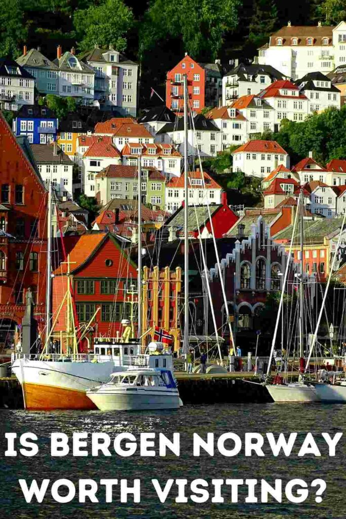 The colorful houses in Bryggen in Bergen (Bergen Wharf) and the characteristic houses in the hillside ascending behind the wharf on a sunny summer day, with boats docked on the wharf in the sun