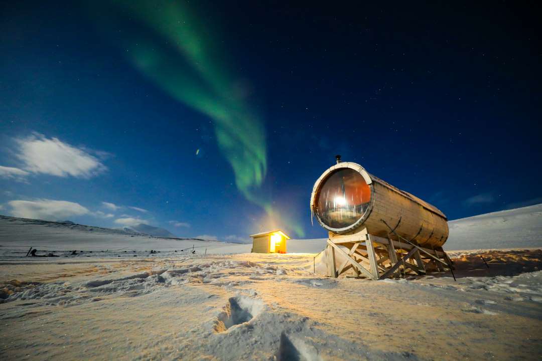 Svalbard in winter with frozen snow coverd plains in the darkness with the green Aurora Borealis dancing across the dark blue sky