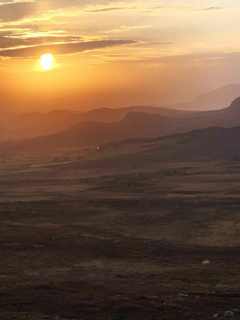 Stunning golden sunset in September in the mountains in Norway with infinite views and the golden sun above the horizon