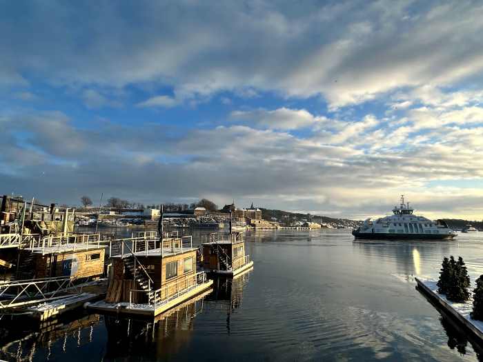 The wooden floating saunas in the oslo fjord on a sunny day, with the fjord ferry in the background 