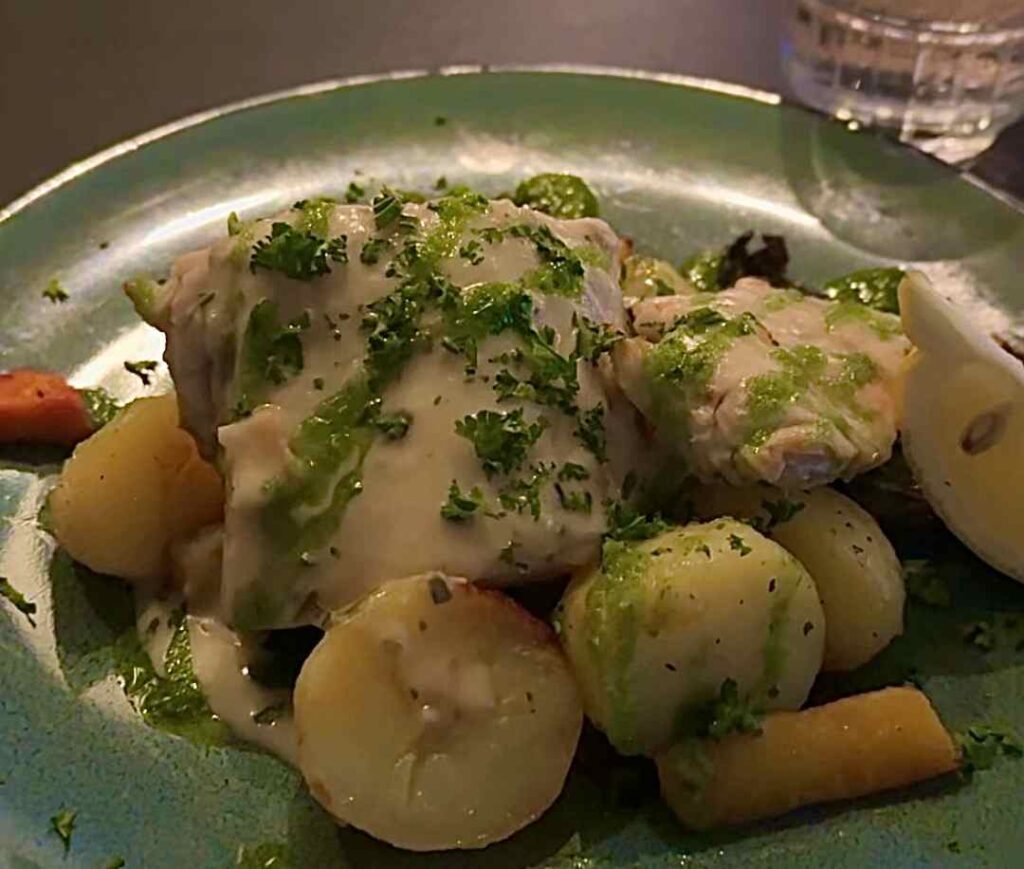 A close up photo of freshly caught cod in Norway, with potatoes, vegetabler, lemon, and green garniture, looking delicious. 