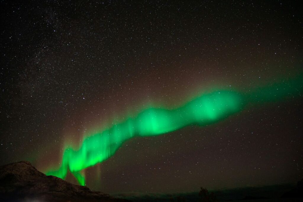 Beautiful northern lights on a dark night sky over a dark mountain