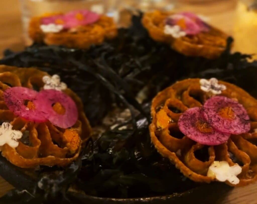 A colorful ard artful decorated meal with pink, orange and white flower decor at Holmen Restaurant in Lofoten, Norway