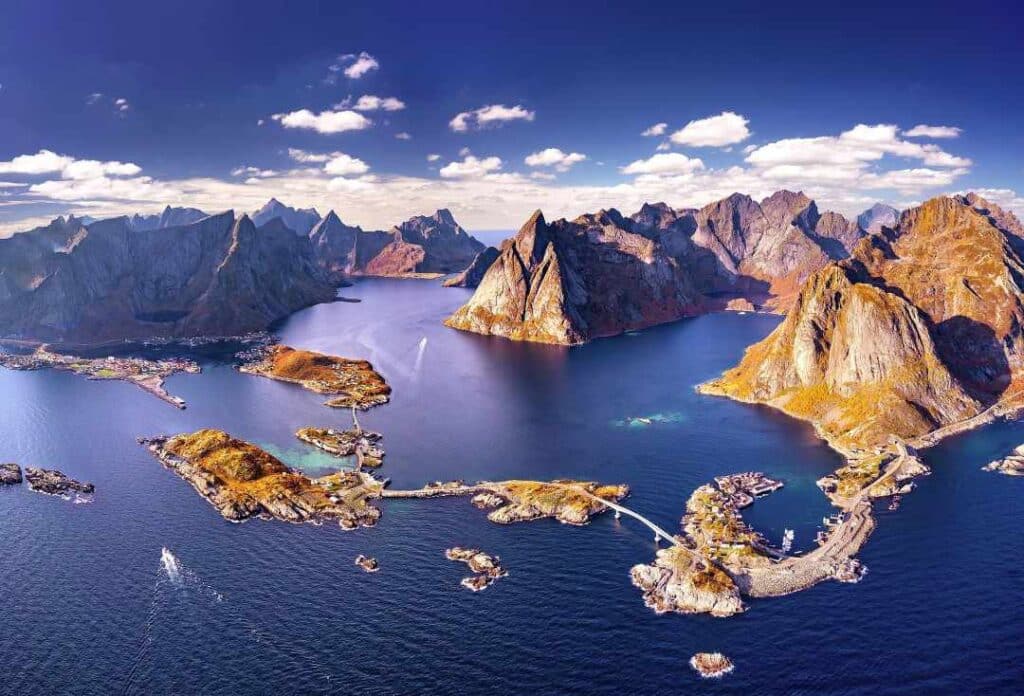 Infinite views of western Lofoten in Norway, with small islets scattered around the fjord, and the vast mountains in the background under a deep blue sky