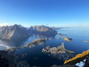 View of a deep blue fjord scattered with small islands and surrounded by majestic mountains under an equally deep blue sky, with stunning infinite views on a sunny summer day. Reinebringen, Reine, Lofoten, Norway.