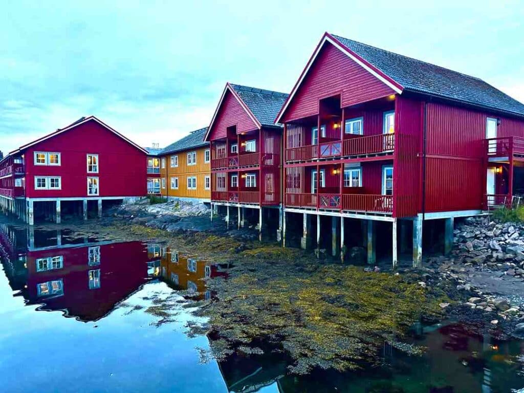 Traditional red wooden fishermans cabins on stilts by the sea under a pale blue sky