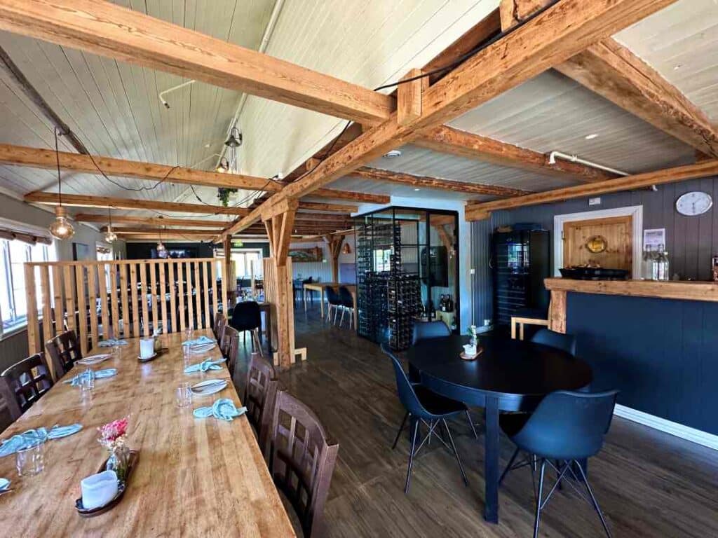 A charming restaurant interior with a mix of modern details in black, and old timber details under a white painted ceiling in Sørvågen, Lofoten, Norway