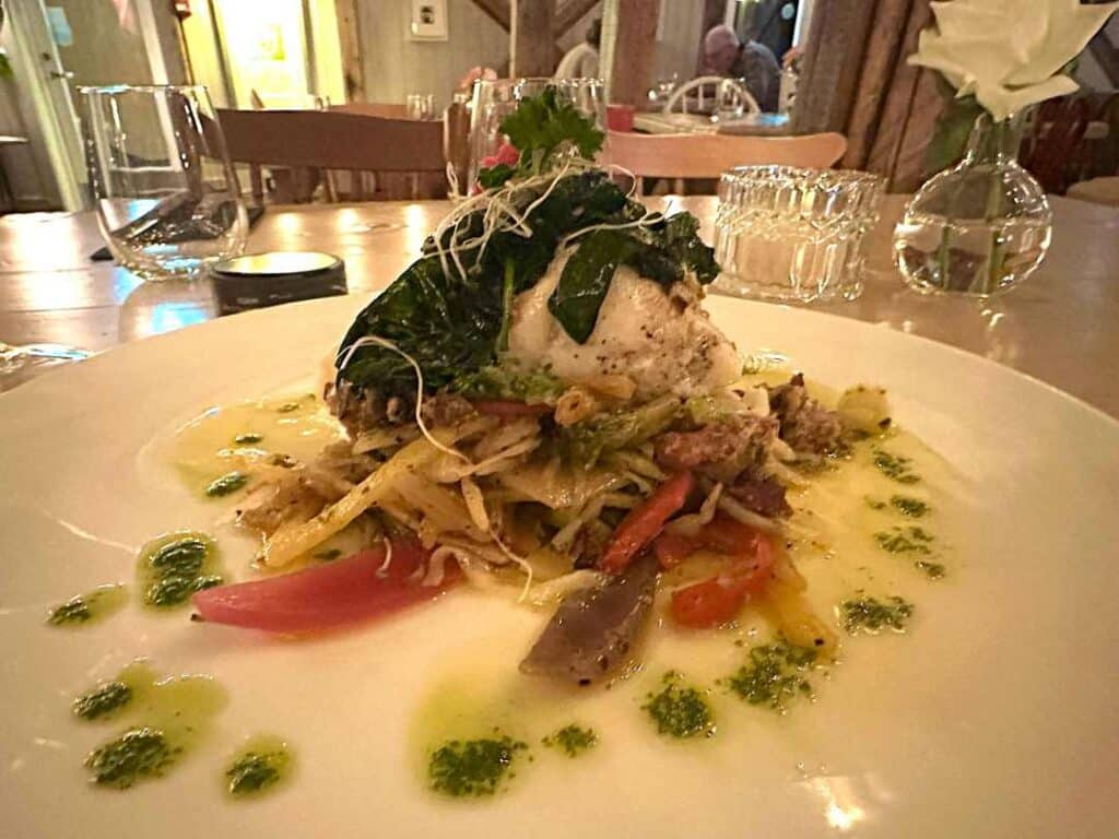 Beautiful fish dish served with elegant presentation and garniture at Underhuset restaurant in Reine Lofoten. This white fish is halibut, cooked to perfection. 