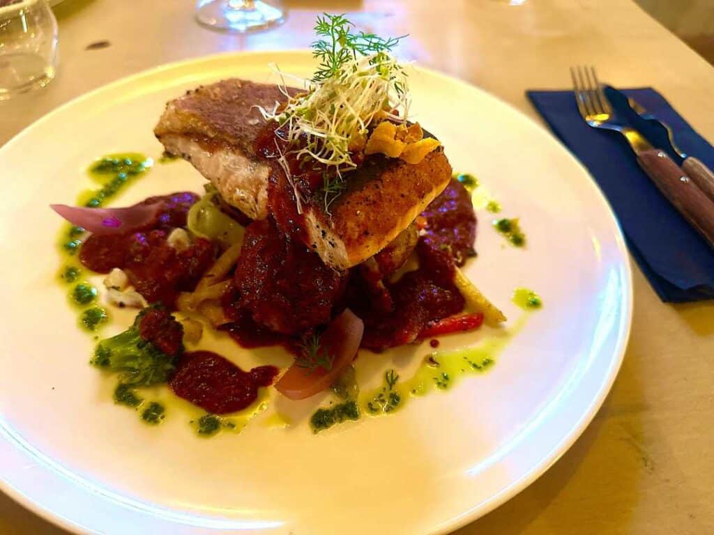 Deliciously presented salmon dinner with fresh vegetables and a green acidic sauce at Underhuset Restaurant in Lofoten, Norway