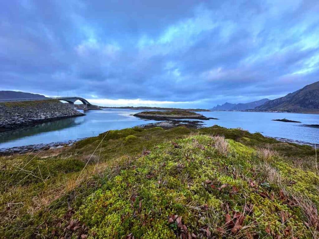 Gloomy autunm weather in Lofoten with green and yellow colors under the deep grey sky, and a bridge between the lofoten islands