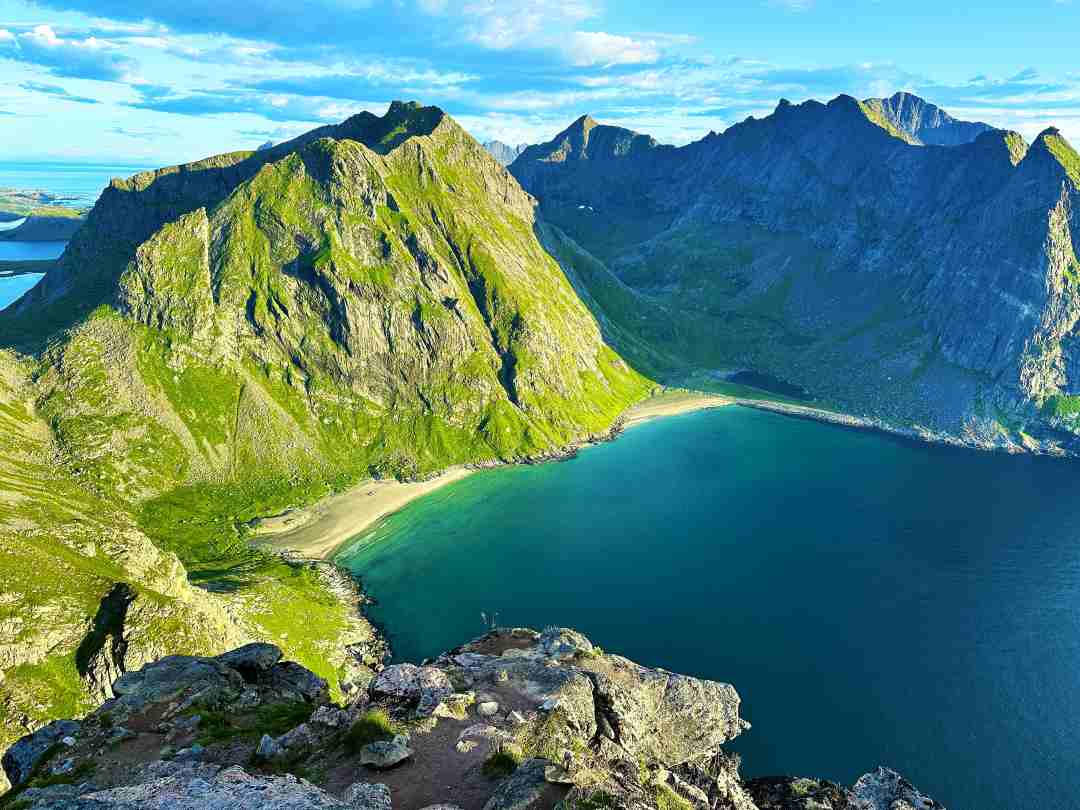 A white sandy beach in warm sunlight under majestic moutnains in Lofoten Norway seen from above on the mountain top Ryten mountain