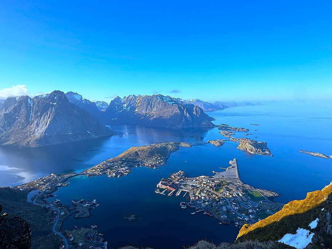 Stunning infinite views of blue seas and blue skies, and mountains like beads on a chain at midnight during summer in the Lofoten Islands Norway