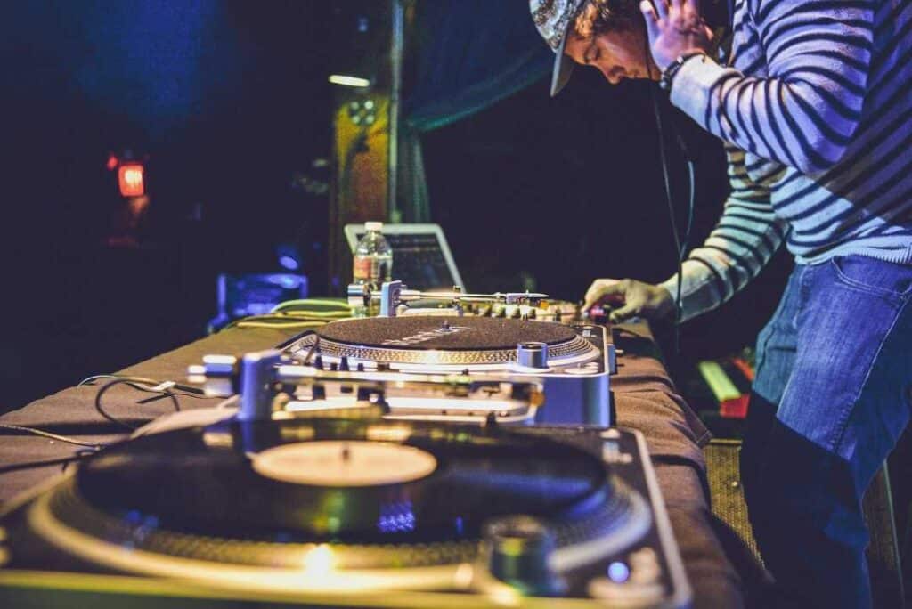 a DJ bent over his mixing board playing music in a night club