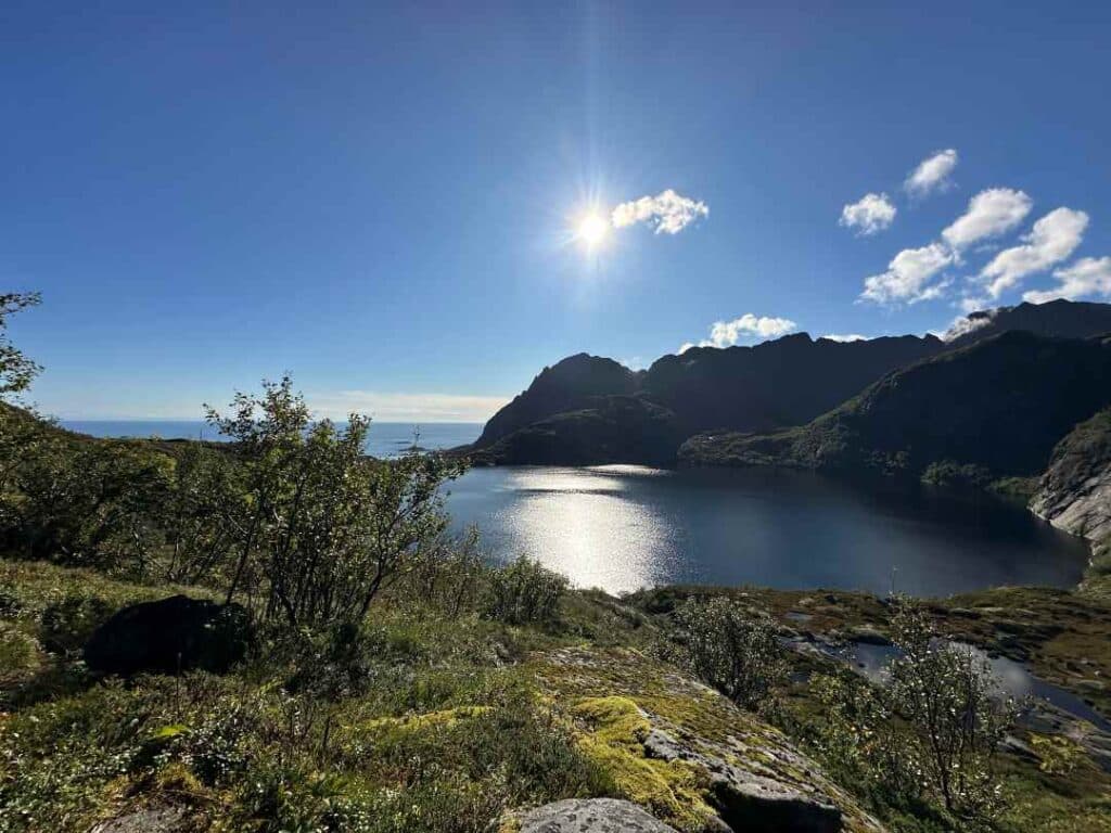 A mountain lake surrounded by grassy hills and mountains under a blue sky on a sunny September day in Lofoten Norway