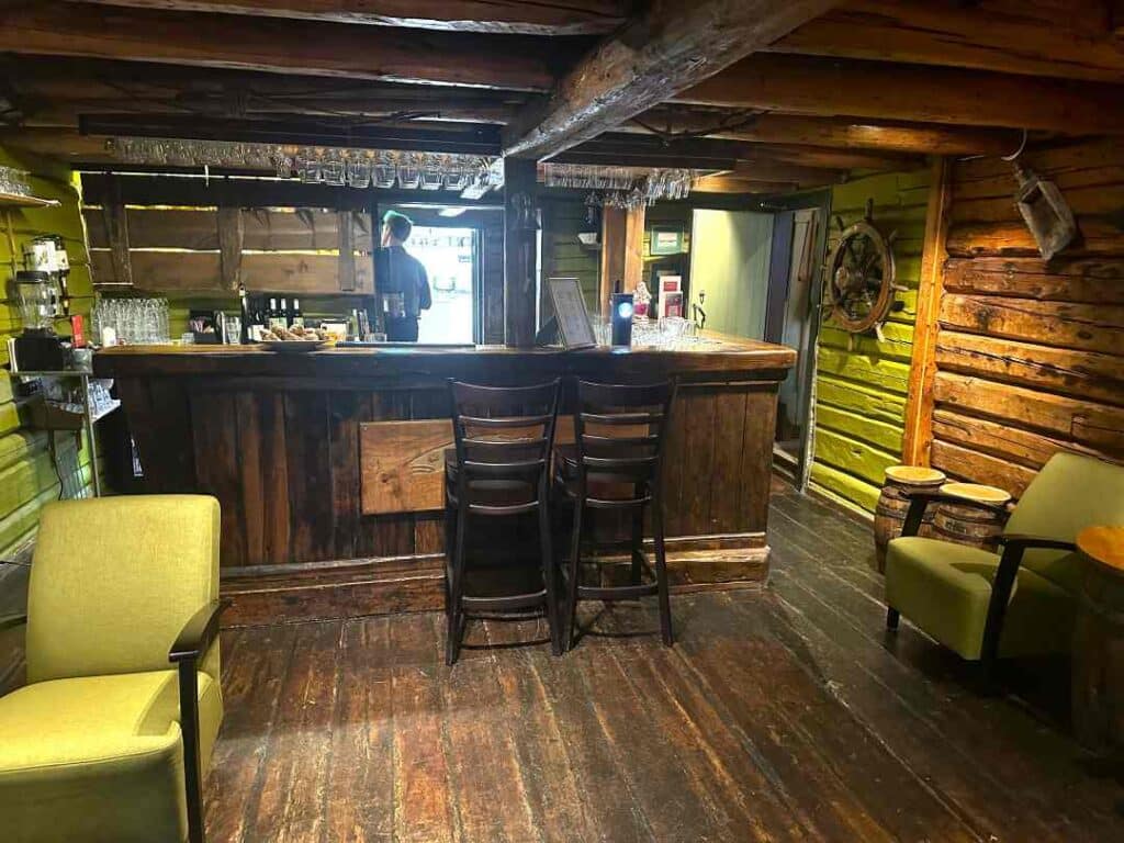 A bar located inside a 200 years old wooden house with solid wooden walls and ceiling, and warm details in the interior and lighting, at Svinøya Rorbuer in Svolvær, Lofoten, Norway