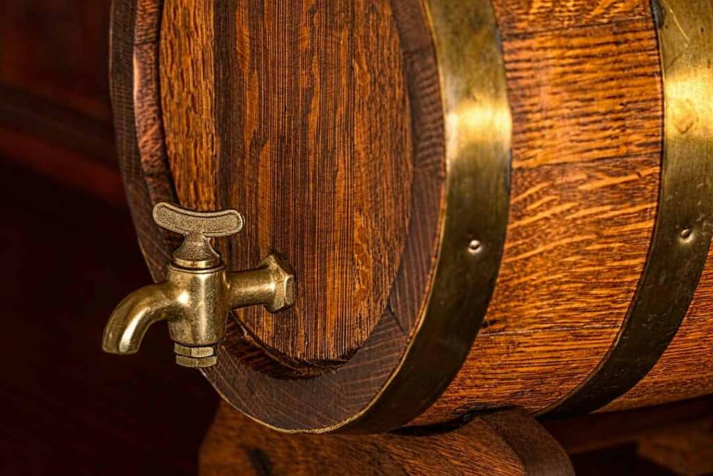 An old fashioned wooden beer barrel with a tap in warm lighting