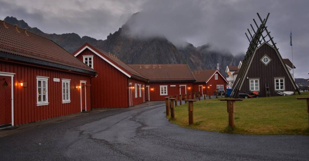 Red fishermans cabin on a grey day in Svolvær Lofoten, with light clouds dancing around the majestic mountains looming over the cabin village